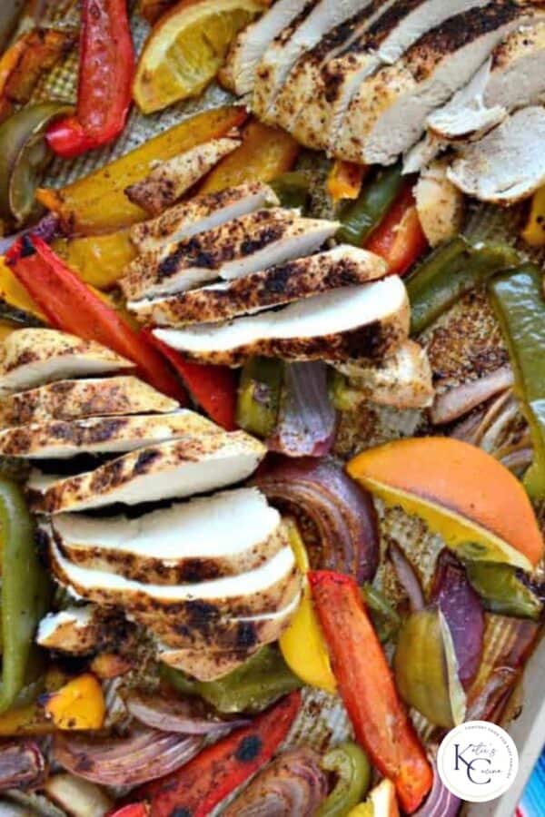 Sliced chicken breast with peppers and onions on a pan.