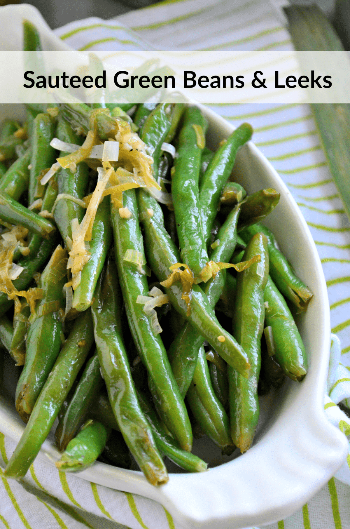 closeup top view of glistening Sauteed Green Beans & Leeks topped with shredded cheese and title text.