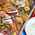 Sheet pan filled with sliced chicken breast, bell peppers, onions, and roasted citrus.