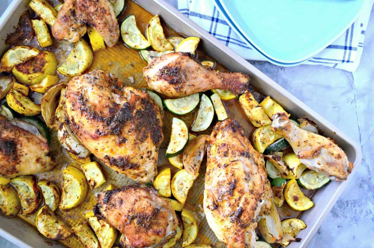 top view of browned chicken and sliced zucchini and squash on sheet pan.