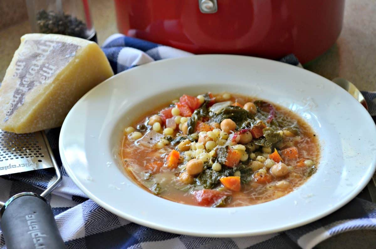 Garbanzo Bean Vegetable Soup with Pearled Couscous in a bowl next to cheese grater and cheese.