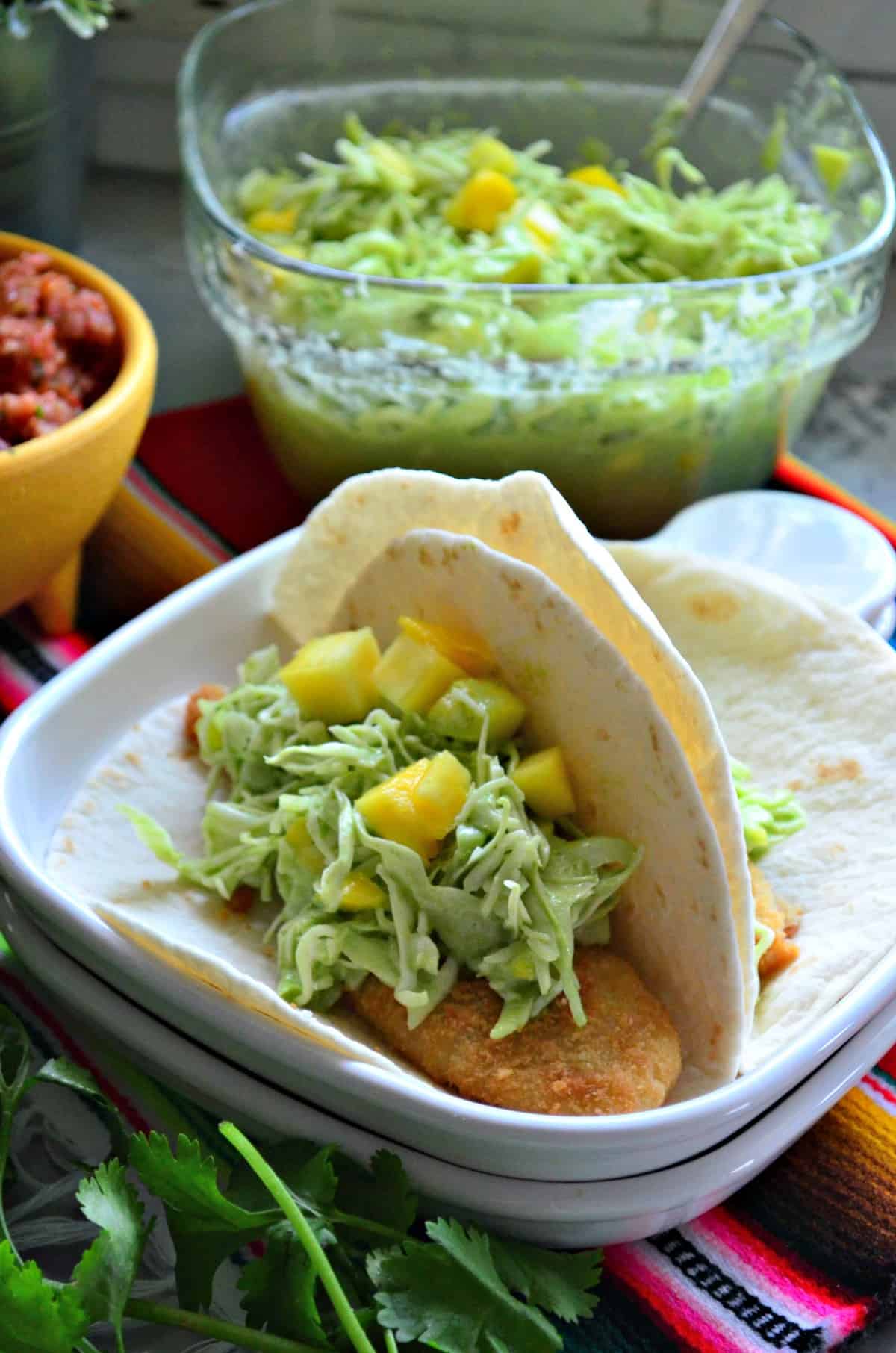 two flour tortilla tacos on plate with mango coleslaw.