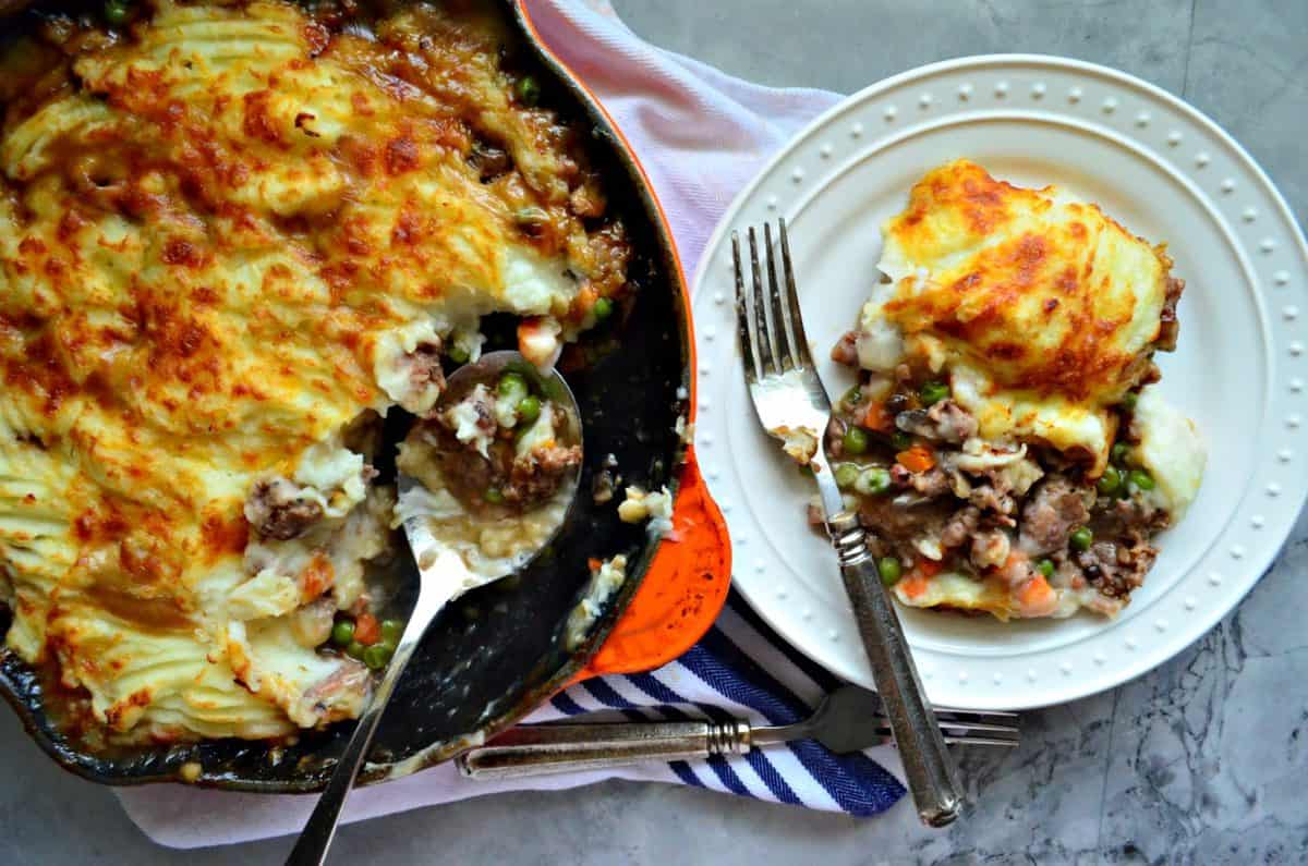 top view of shepards pie in skillet with spoon and ⅓  of contents on a plate next to skillet.