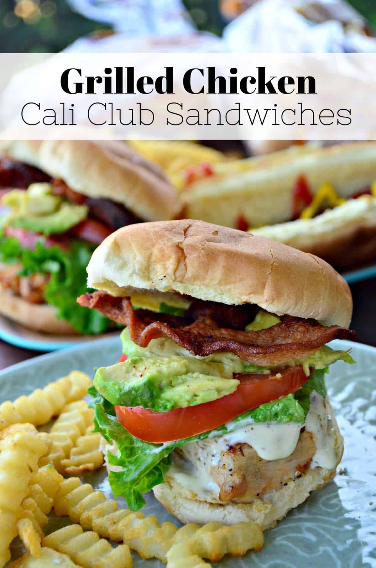 chicken, ranch, lettuce, tomato, bacon, and avocado on a bun with fries on a plate.