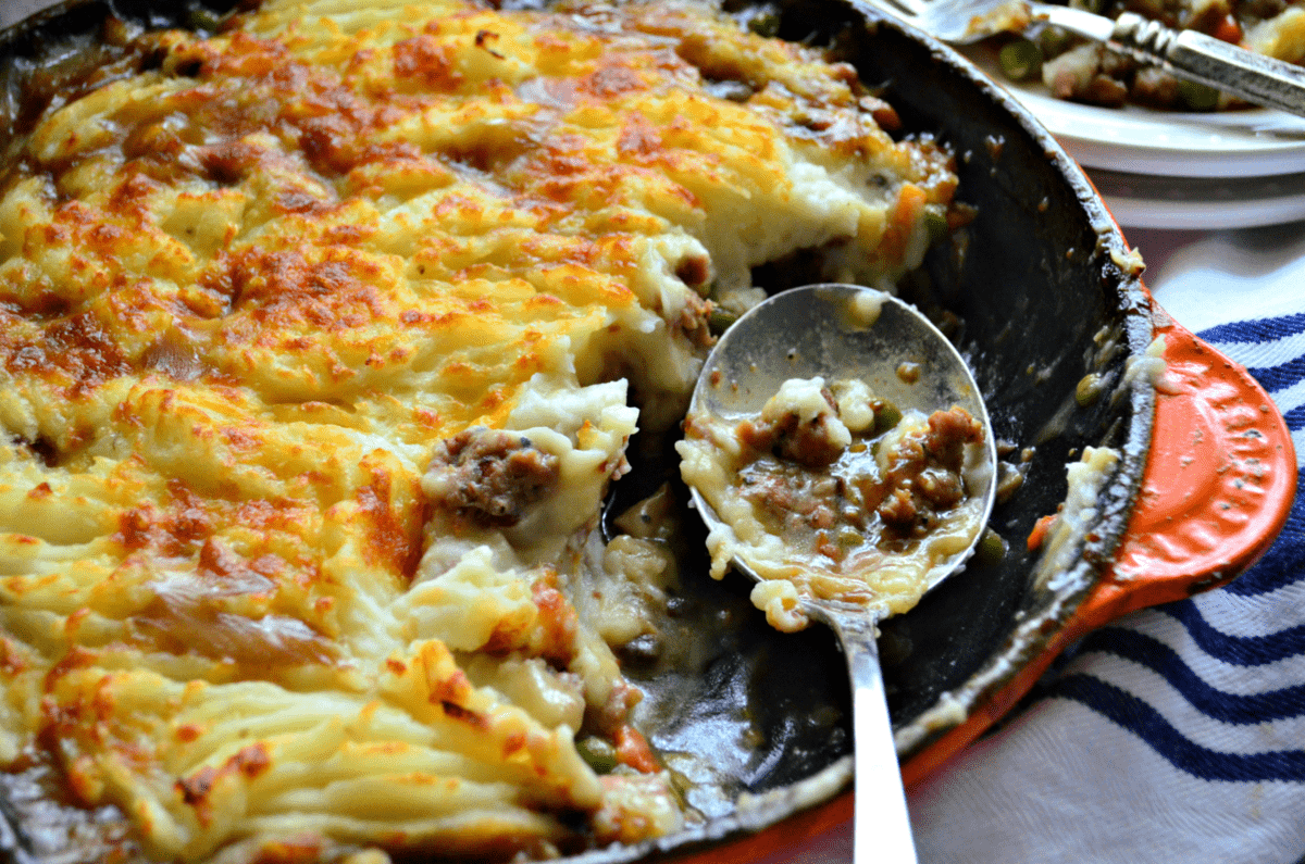 top view of shepards pie in skilled with several spoonfuls missing and spoon sitting in it.