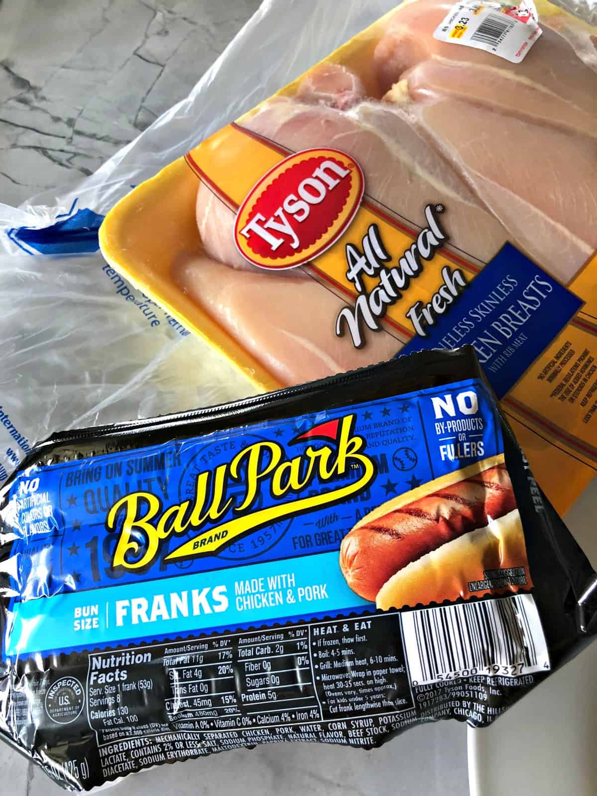 package of tyson all natural chicken breasts next to package of ballpark franks.