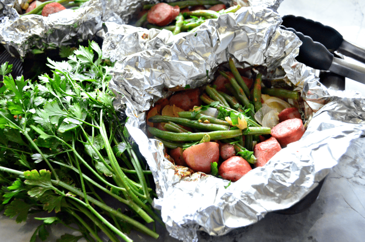 Grilled Kielbasa, Potato, green beans, and parsley in Foil Packet next to fresh parsley.