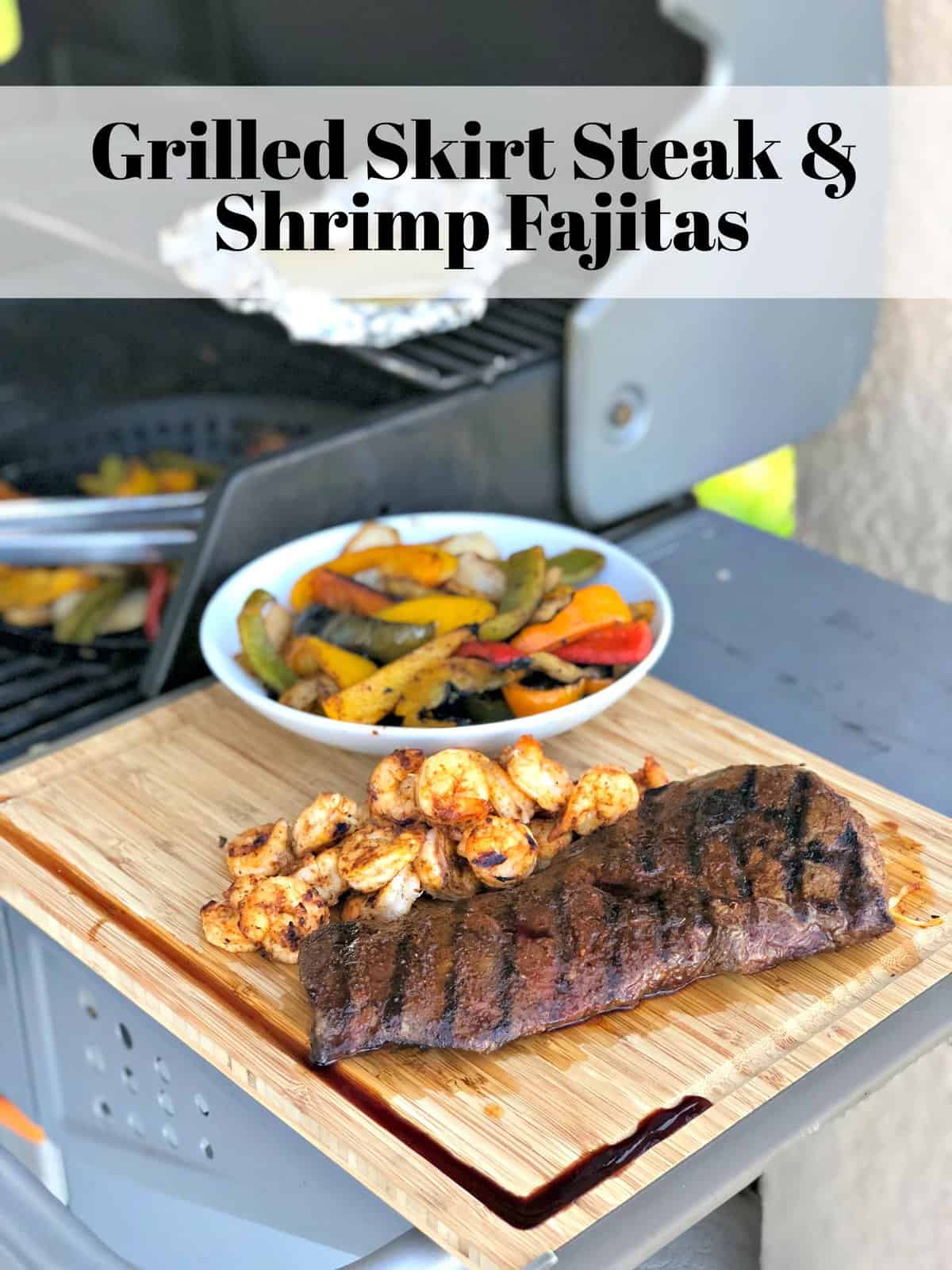 Grilled Skirt Steak next to grilled shrimp and peppers on wooden board with title text next to grill.