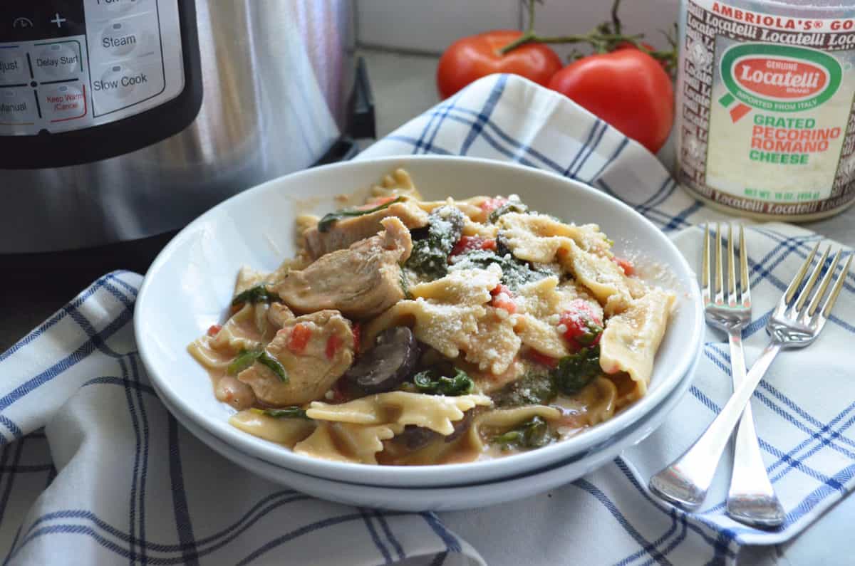 bowl of bowtie pasta with chicken, mushroom, spinach, tomato, and cheese.