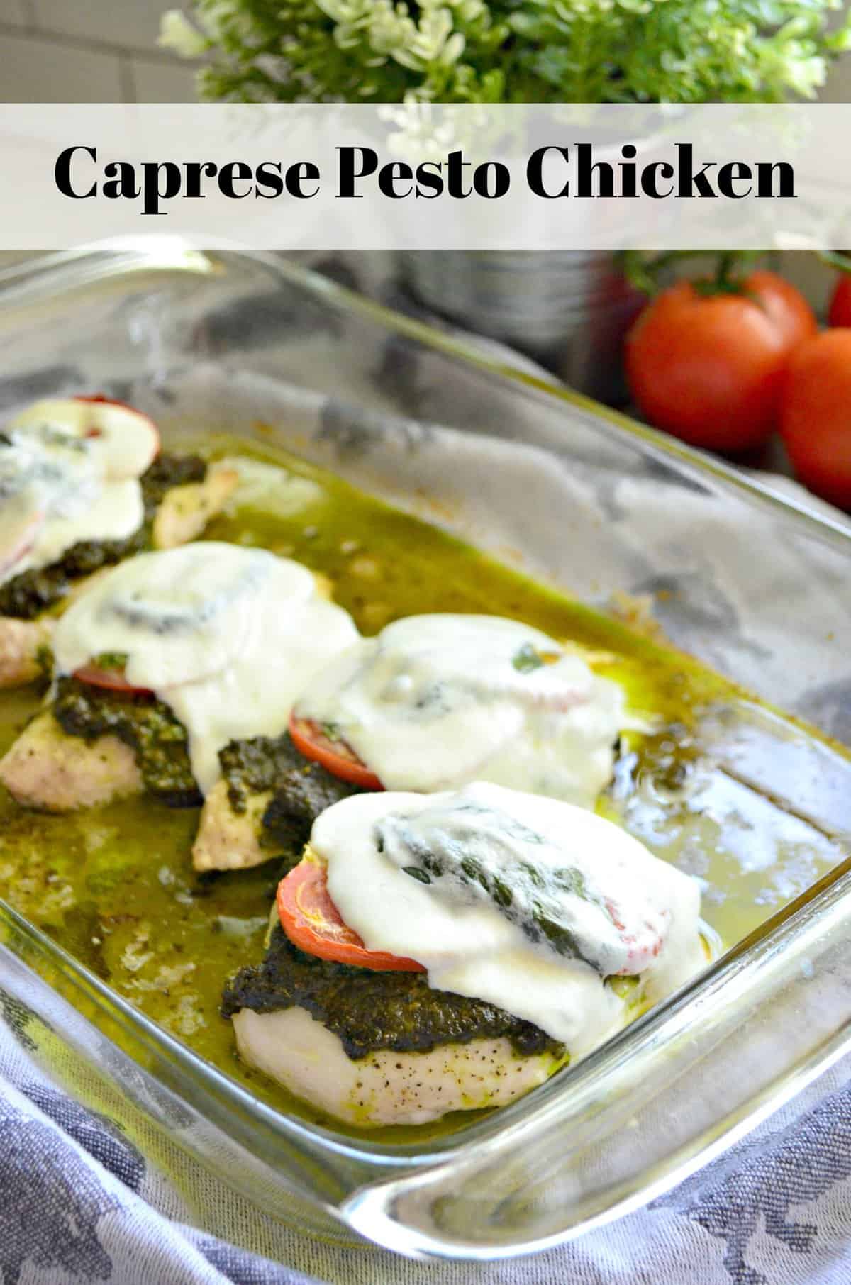 4 pieces of chicken topped with pesto, tomato, mozzarella, and basil in glass baking dish.