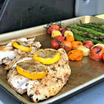 Baking sheet with snapper, blistered tomatoes, and asparagus.