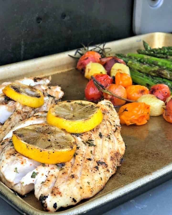 Baking sheet with snapper, blistered tomatoes, and asparagus.