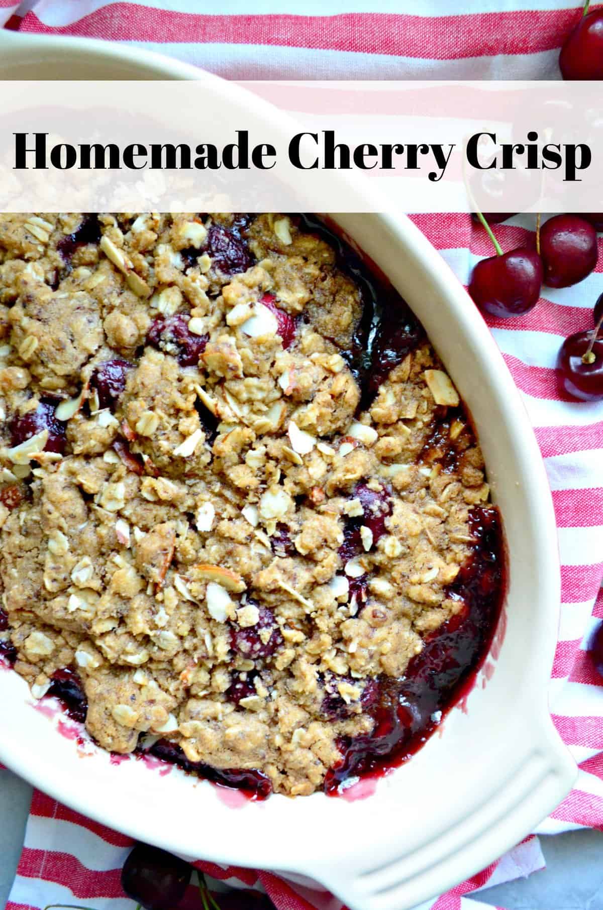 Overhead view of cherry crisp with sliced almonds on a red and white striped cloth with text.