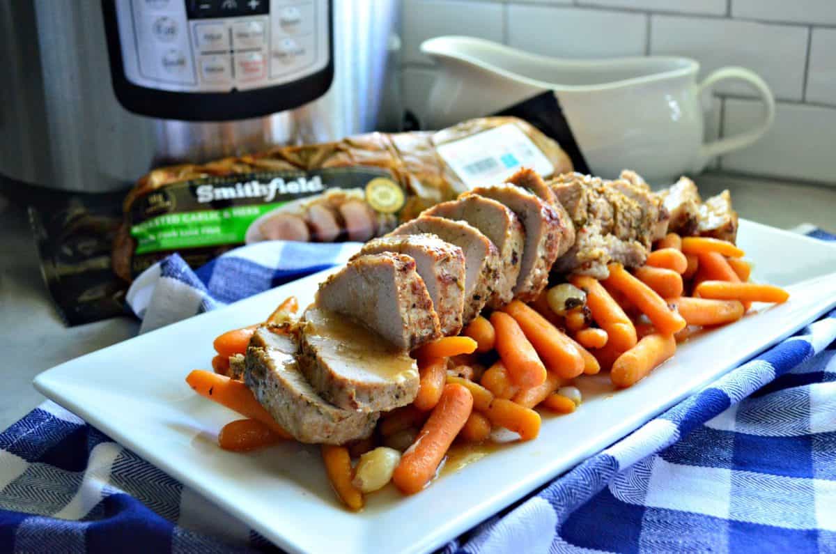 Garlic and Herb Pork Tenderloin with Carrots and Pearl Onions on platter in front of instant pot.