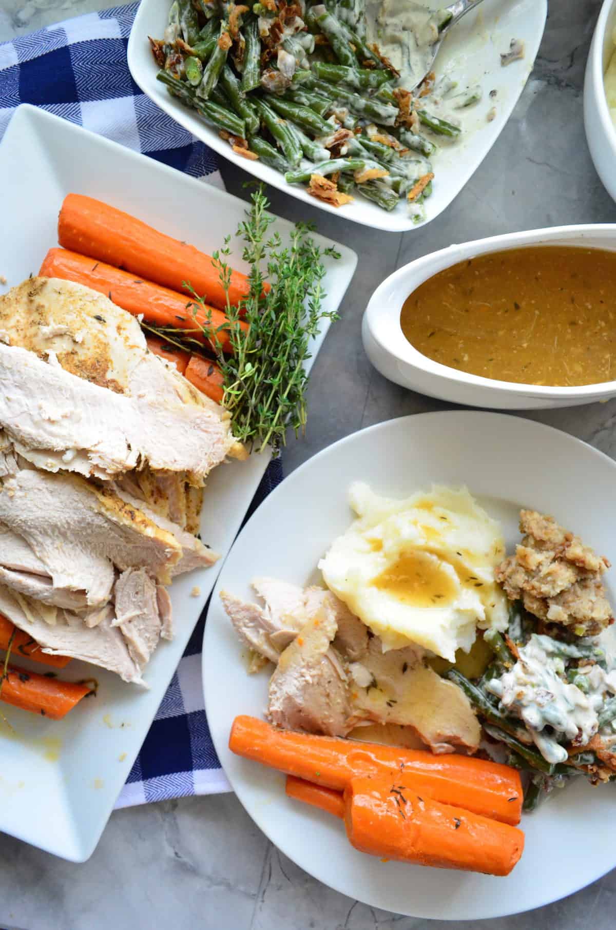 gravy boat, turkey platter, green bean casserole, and plate of turkey, carrots, potatoes, and green beans.