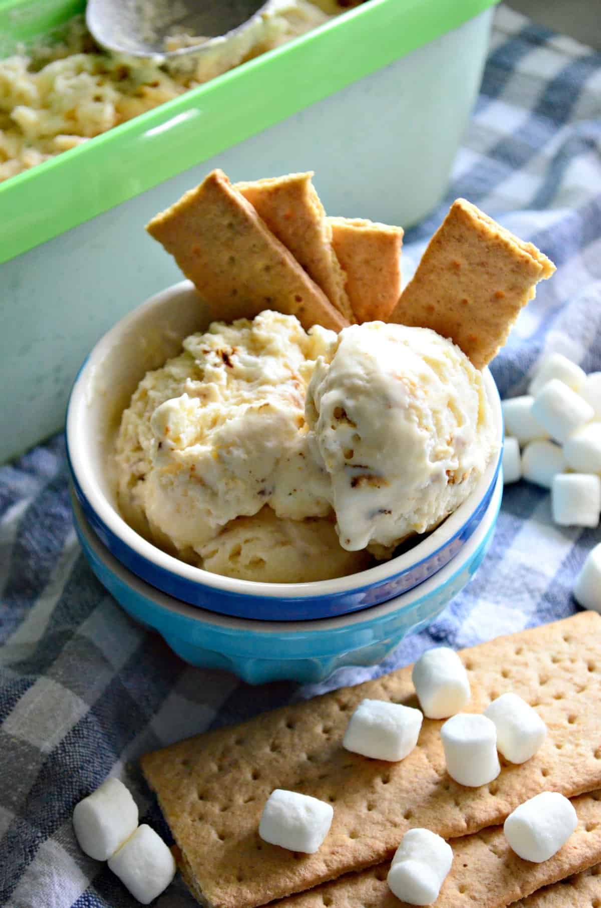 bowl of creamy colored chunky ice cream with graham crackers next to mini marshmallows.