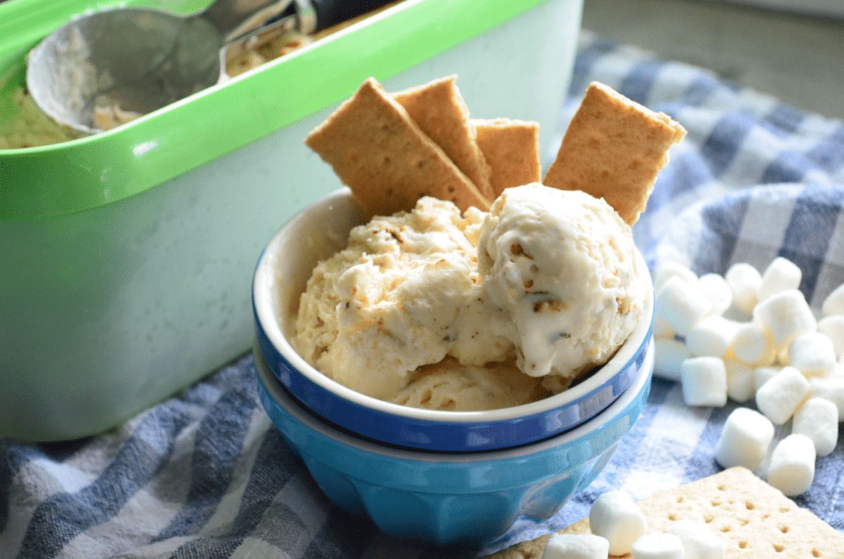 bowl of creamy colored chunky ice cream with graham crackers next to container of more ice cream.