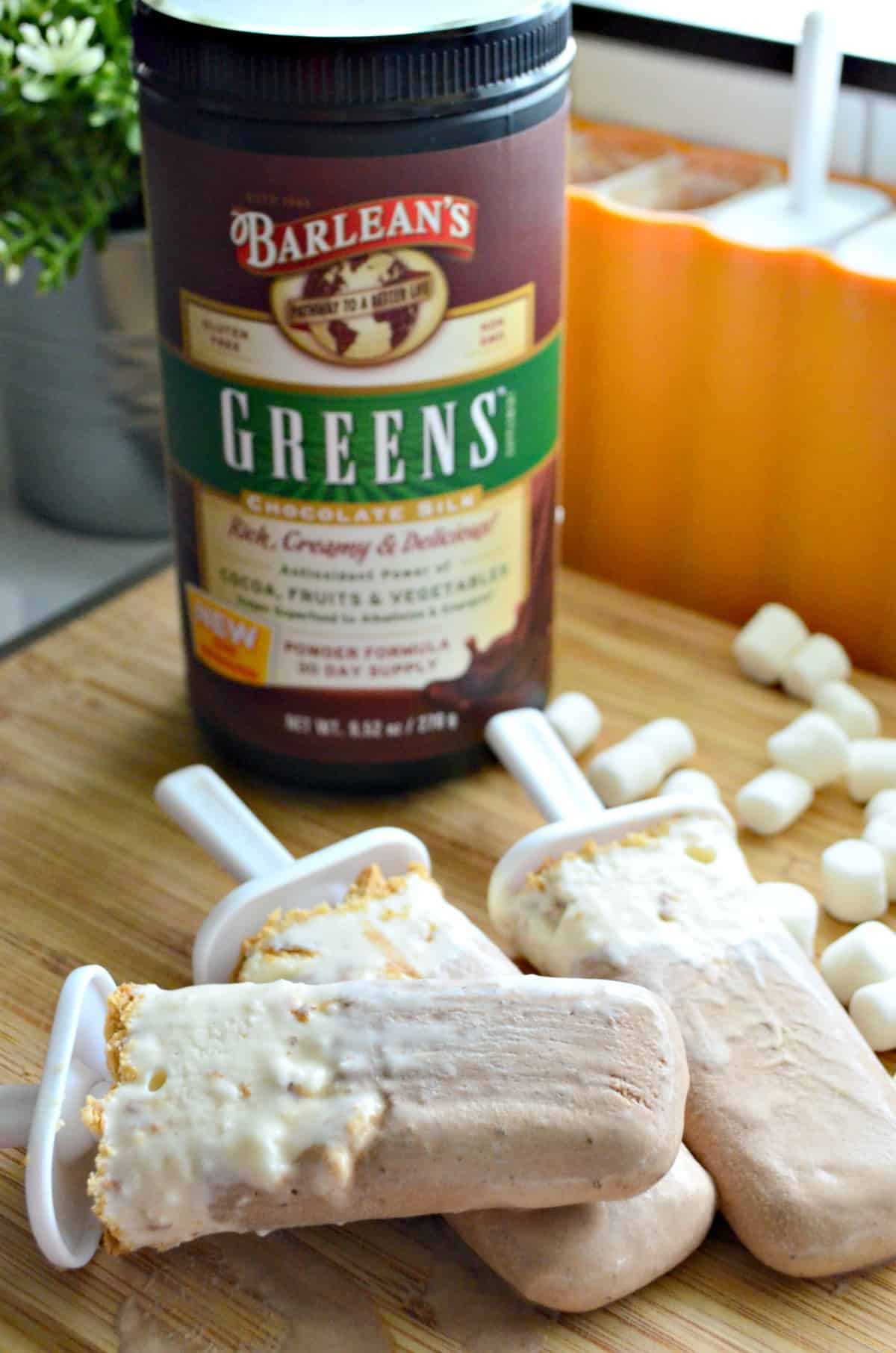 3 light brown and white popsicles on countertop with mini marshmallows and Barlean's Greens chocolate silk.