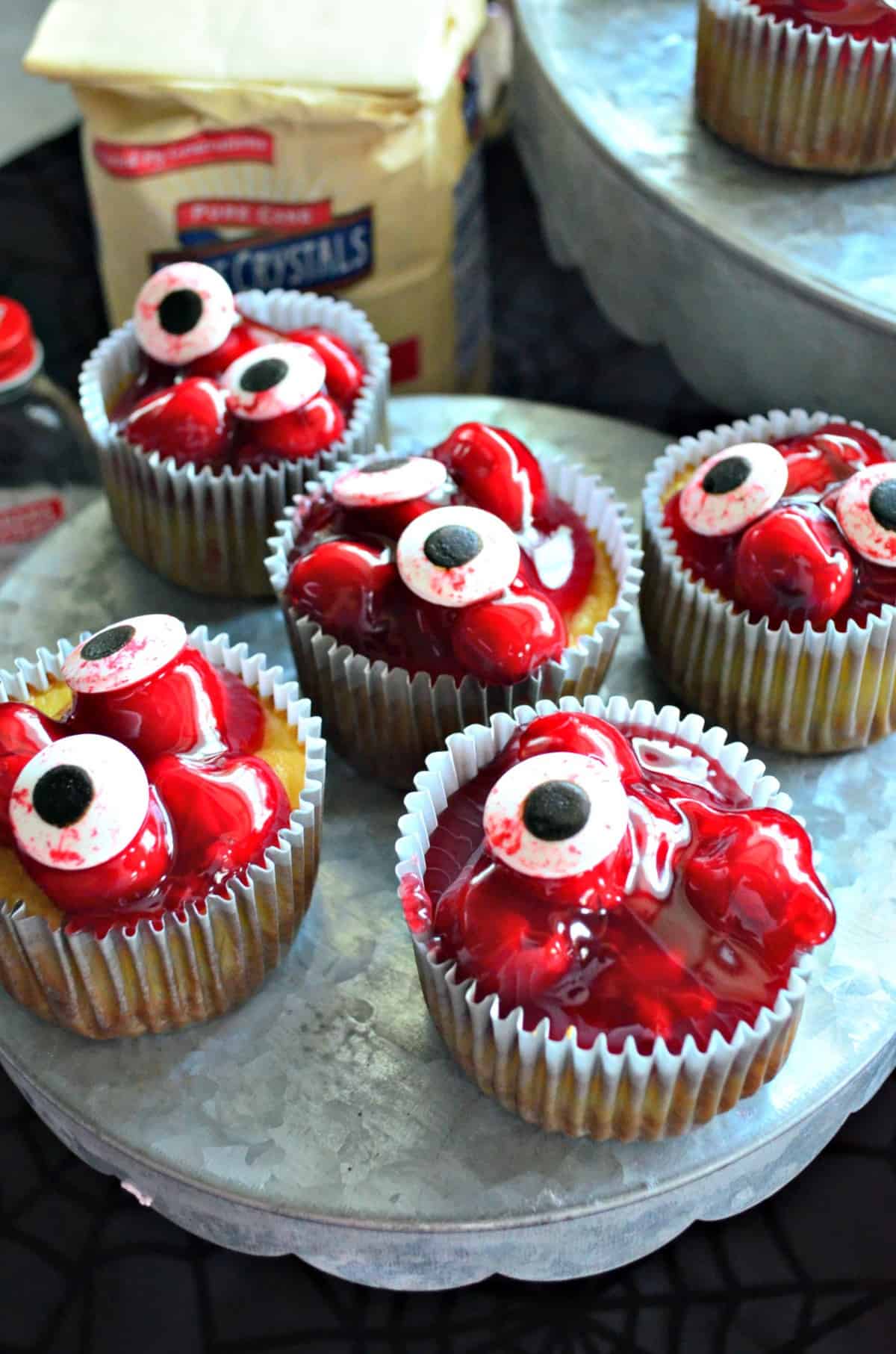 5 cupcakes on cupcake stand topped with red cherries in glaze with candy eyeballs on top and title text.