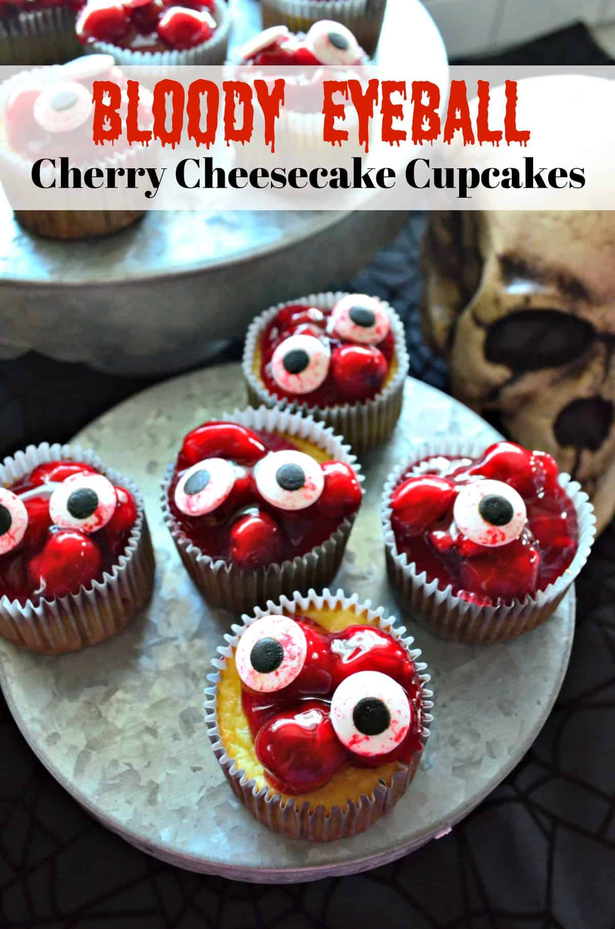 5 cupcakes on cupcake stand topped with red cherries in glaze with candy eyeballs on top.