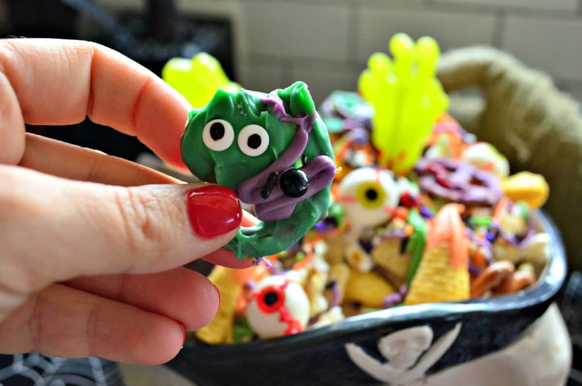 closeup of pretzel covered in green and purple chocolate with candy eyes.