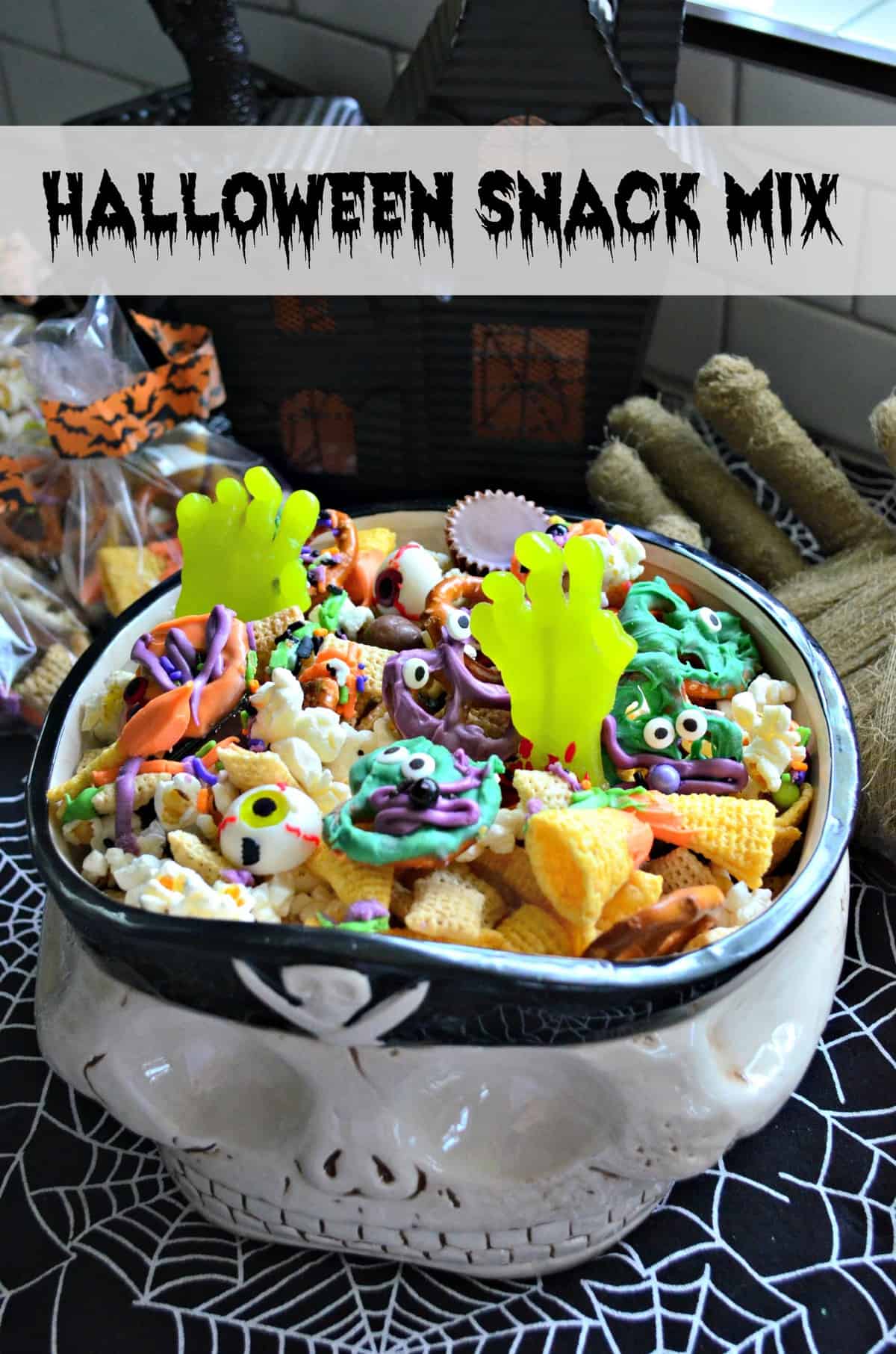 skull bowl of snack mix with colorful chocolate dipped pretzels and candy eyes with title text.