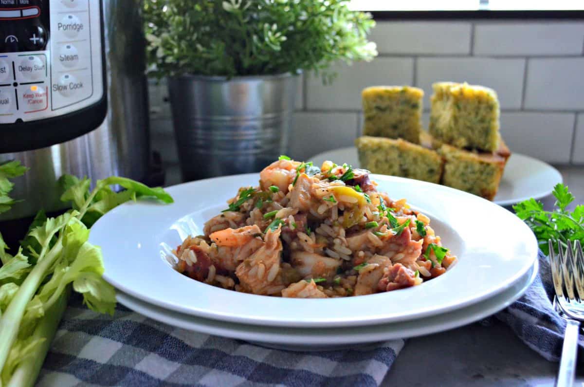 Side view of Chicken, Andouille Sausage, and Shrimp Jambalaya in a bowl with rice on tablecloth.