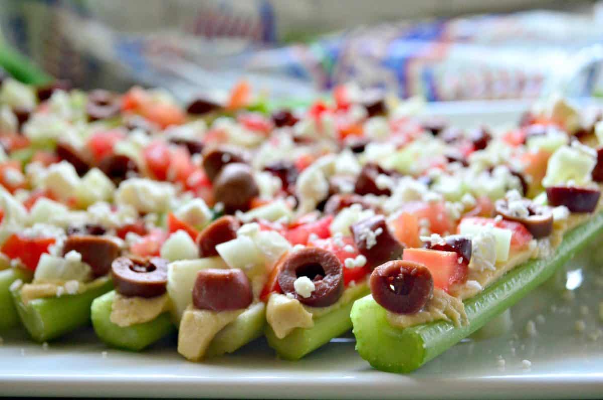 A try full of celery stuffed with hummus, cucumber, tomatoes, and kamalata olives with feta. 