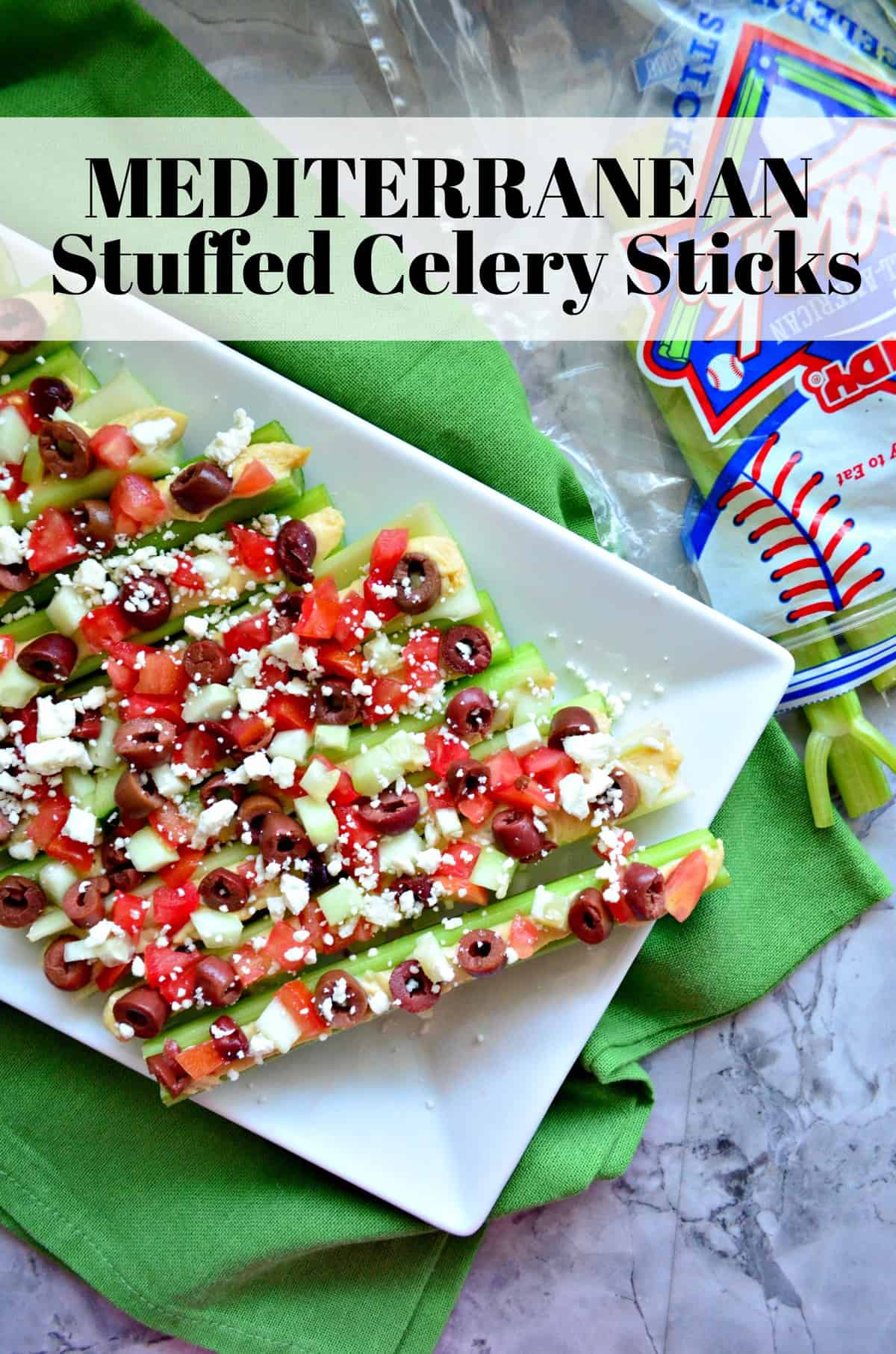 Plated celery sticks stuffed with hummus, feta, kalamata, and tomato with title text.