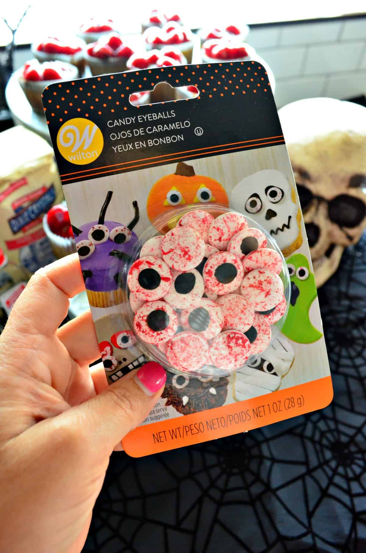 hand holding up package of Wilton Candy Eyeballs.