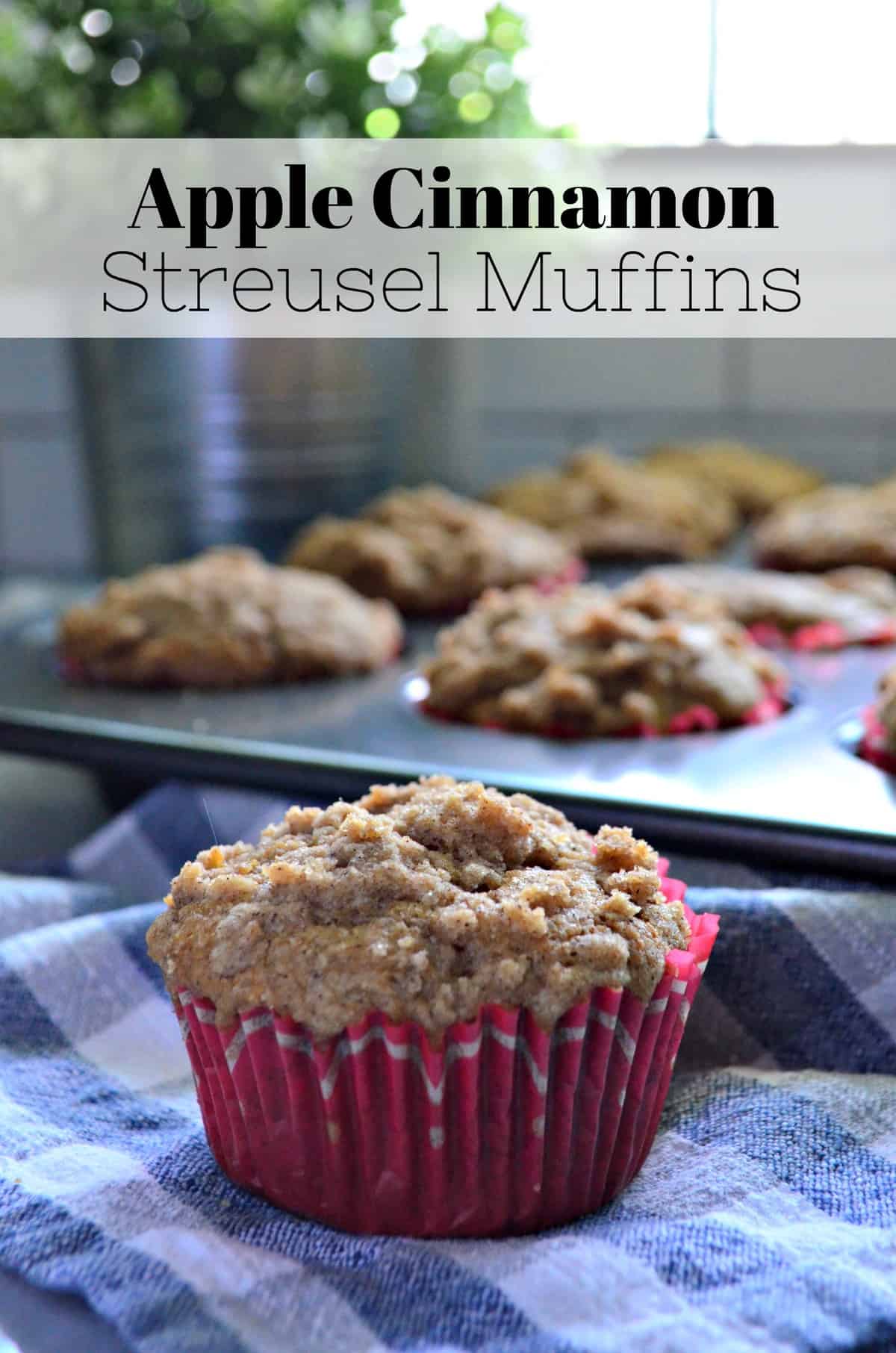 closeup apple streusel muffin in red muffin cup with muffin tin in background with title text.
