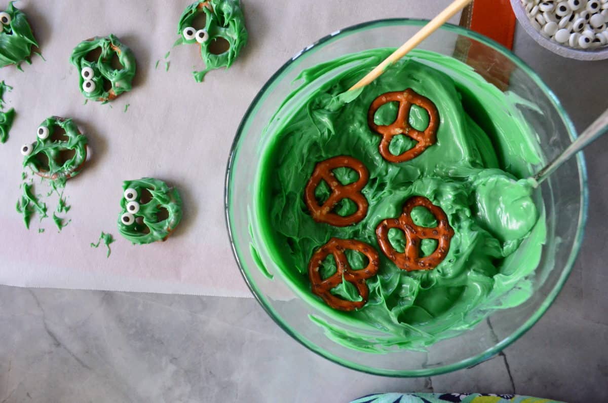 Chocolate Covered Pretzel Monster Bites dipping in white chocolate.