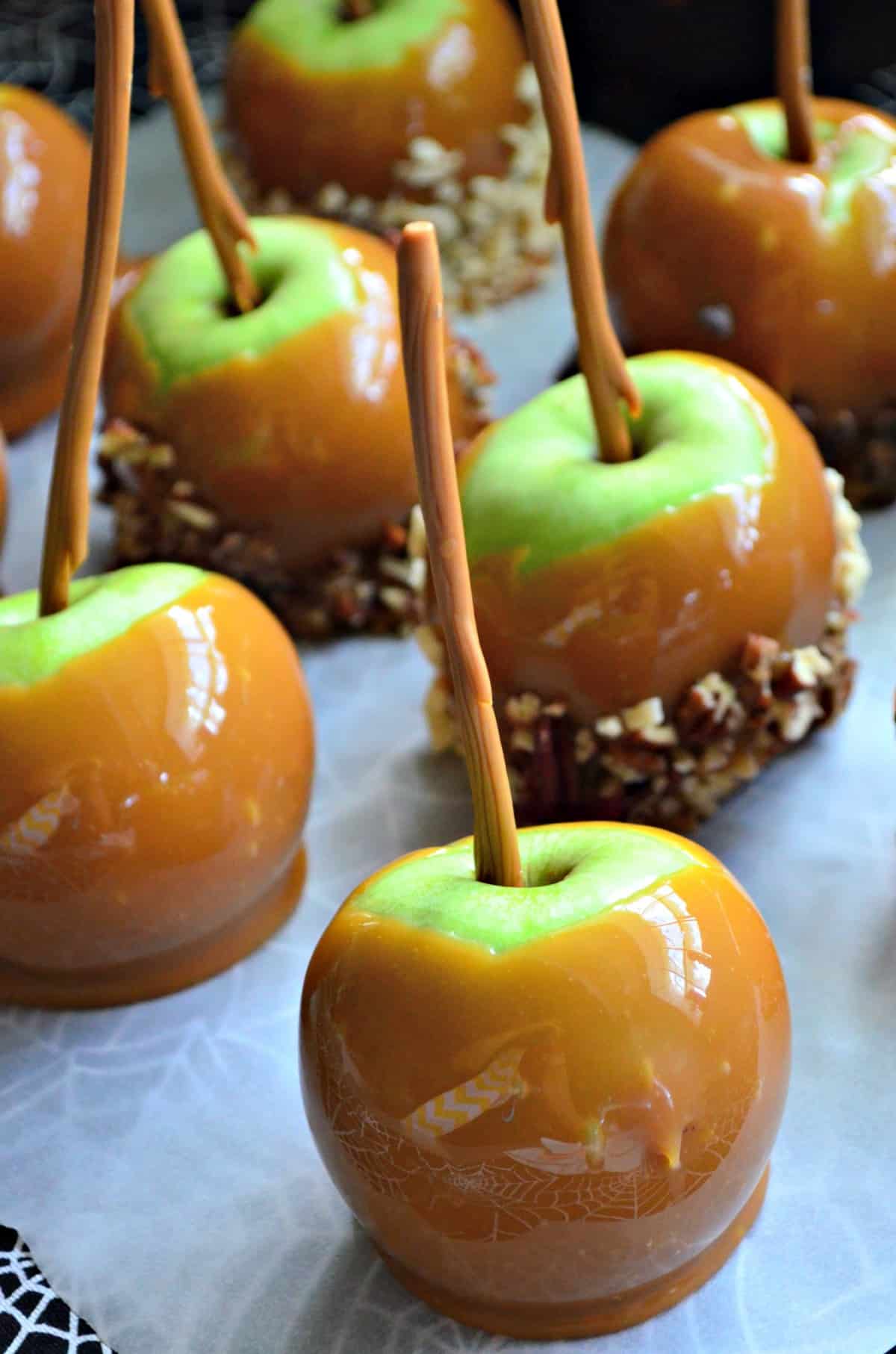 close up of green apples dipped in caramel, some with nuts.