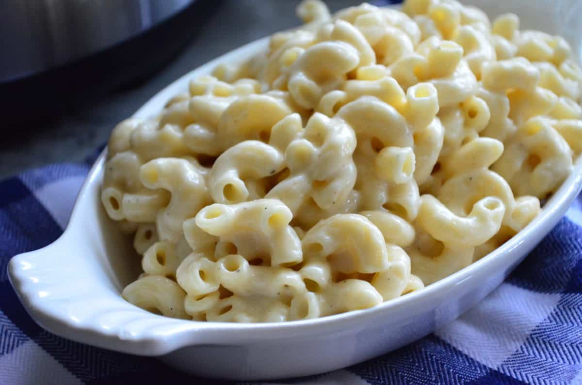 oval platter filled with white macaroni and cheese in front of instant pot and cabot shredded cheese.