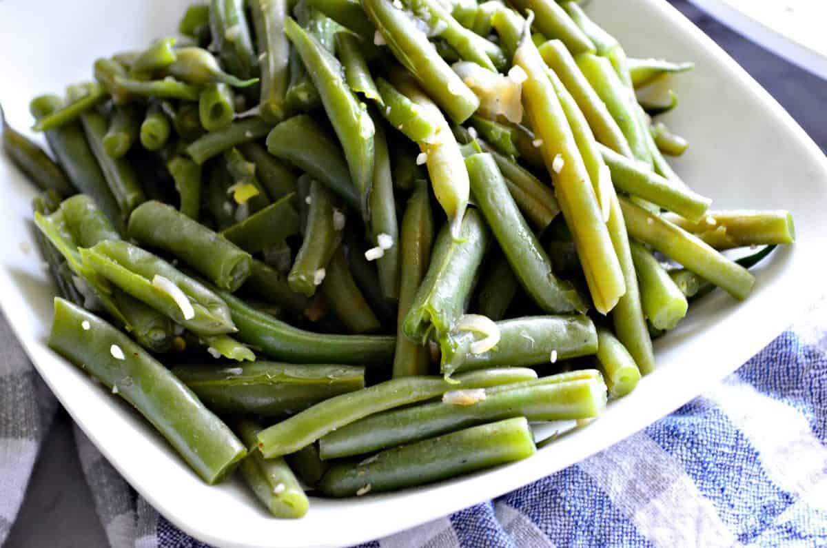 plated cooked green beans with minced garlic on top.