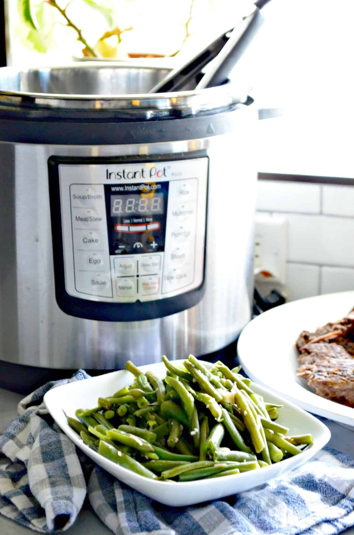 Plated cooked green beans in front of instant pot. 