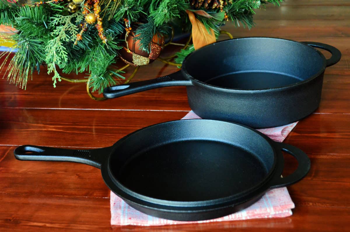 AmazonBasics Pre-Seasoned Cast Iron Skillet and Dutch Oven Set on hardwood floor.
