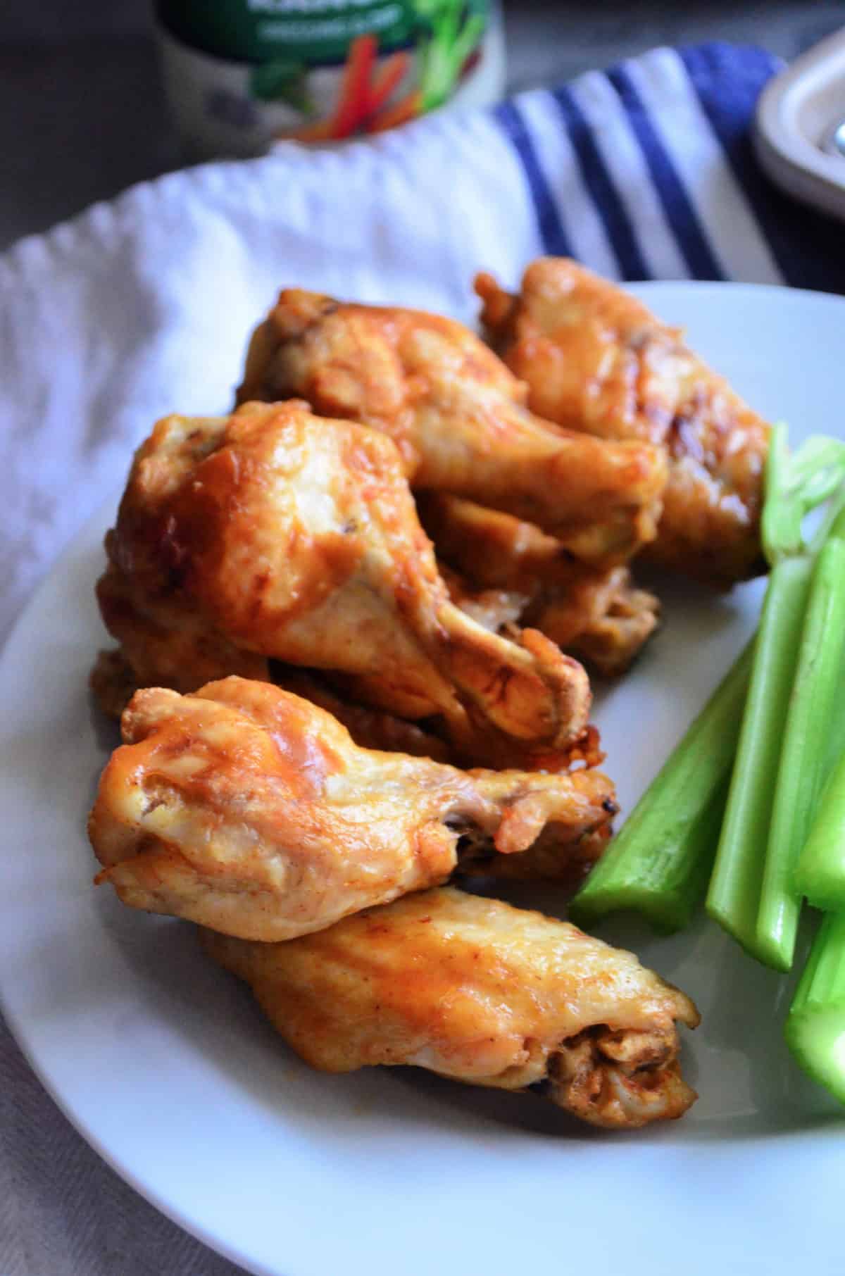 stack of chicken wings on plat next to celery.