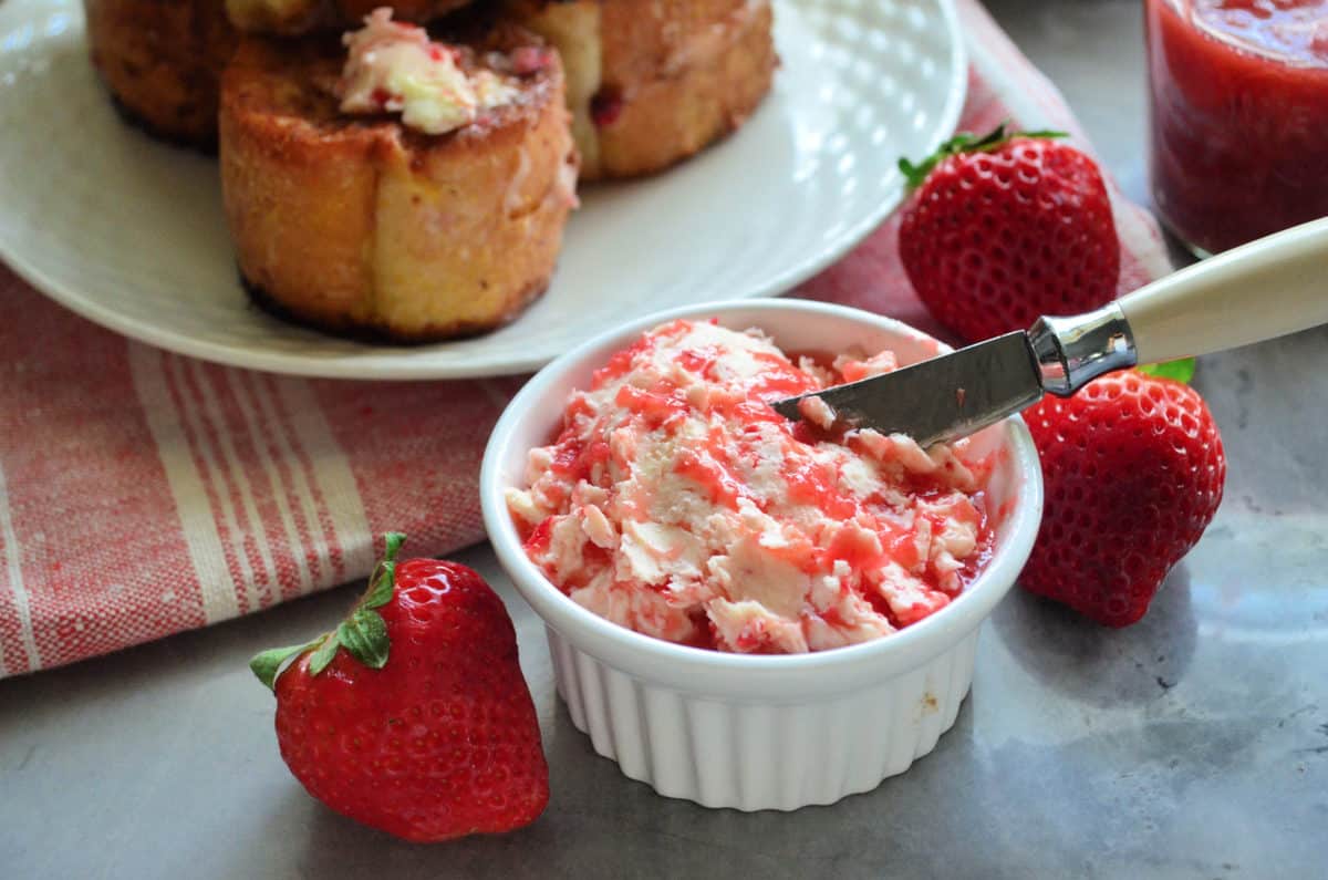 small bowl of chopped strawberries mixed with butter next to fresh strawberries.