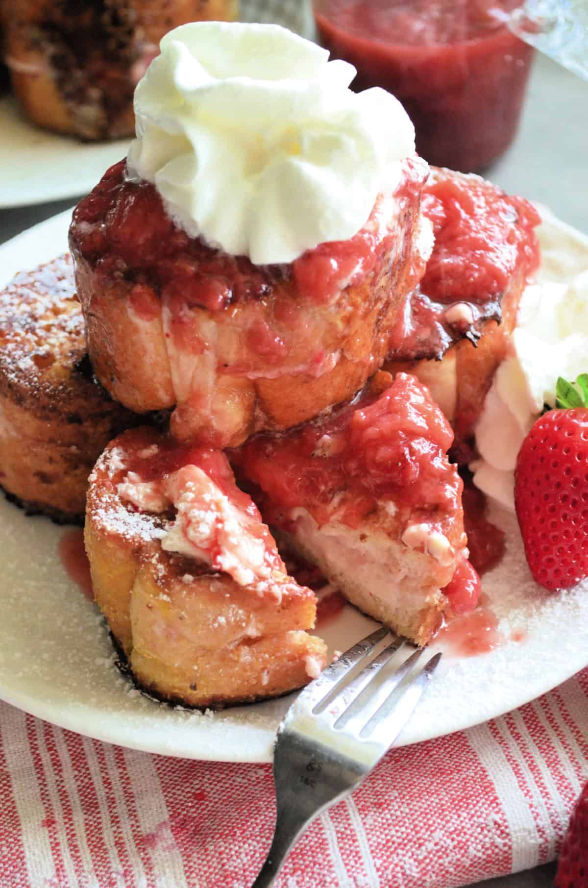 closeup stacked Strawberry Cream Cheese Stuffed French Toast with whipped cream and strawberries.