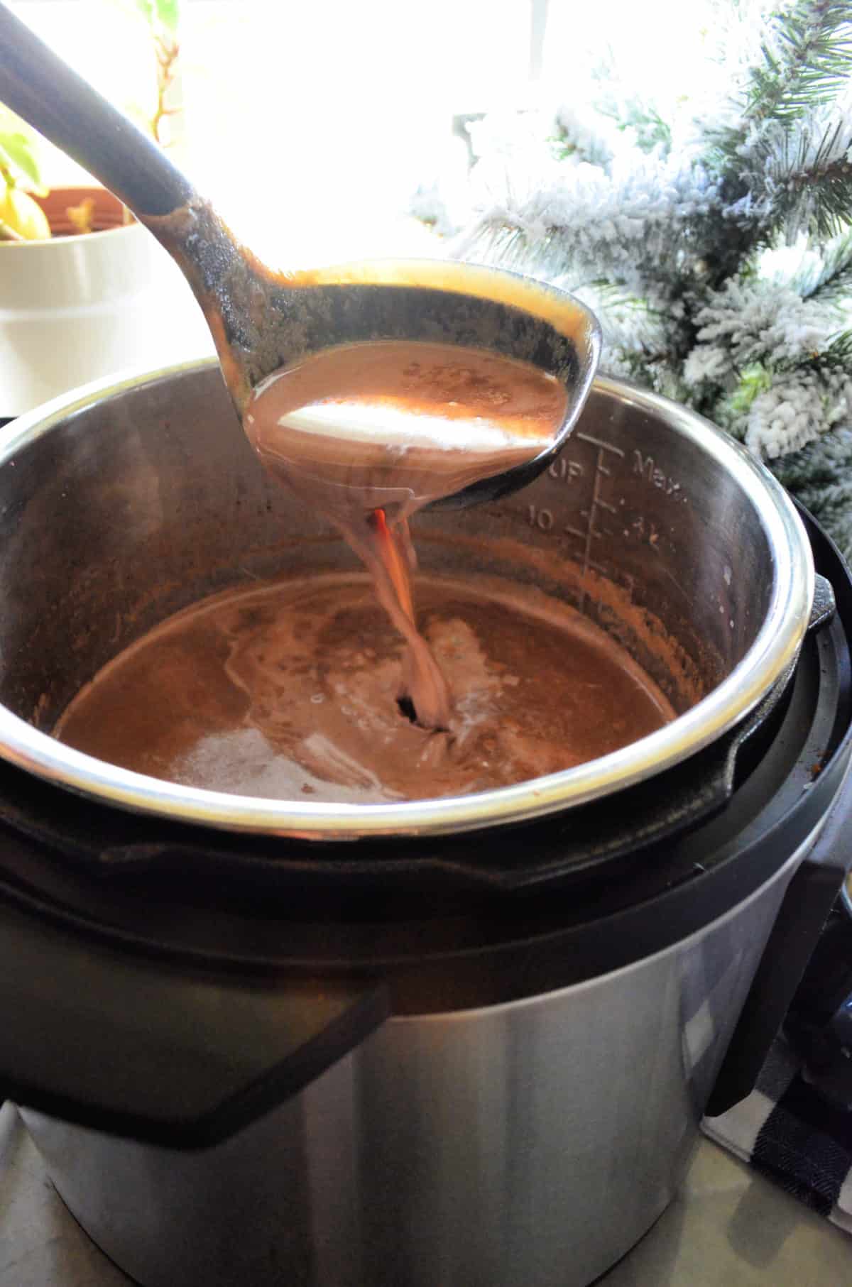 spoon ladling hot chocolate from the instant pot full of brown liquid.