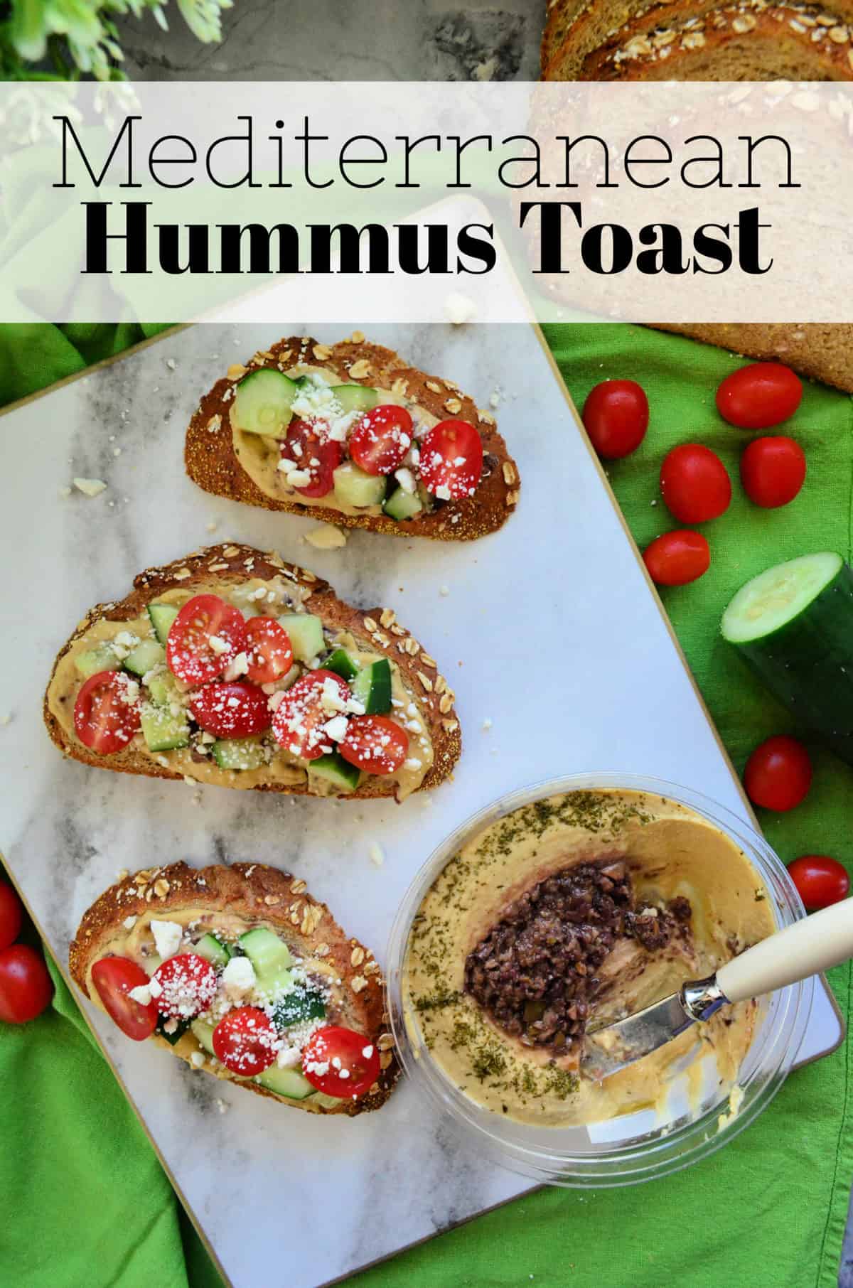 3 toast slices topped with hummus, cucumber, tomato, and feta next to hummus container with title text.