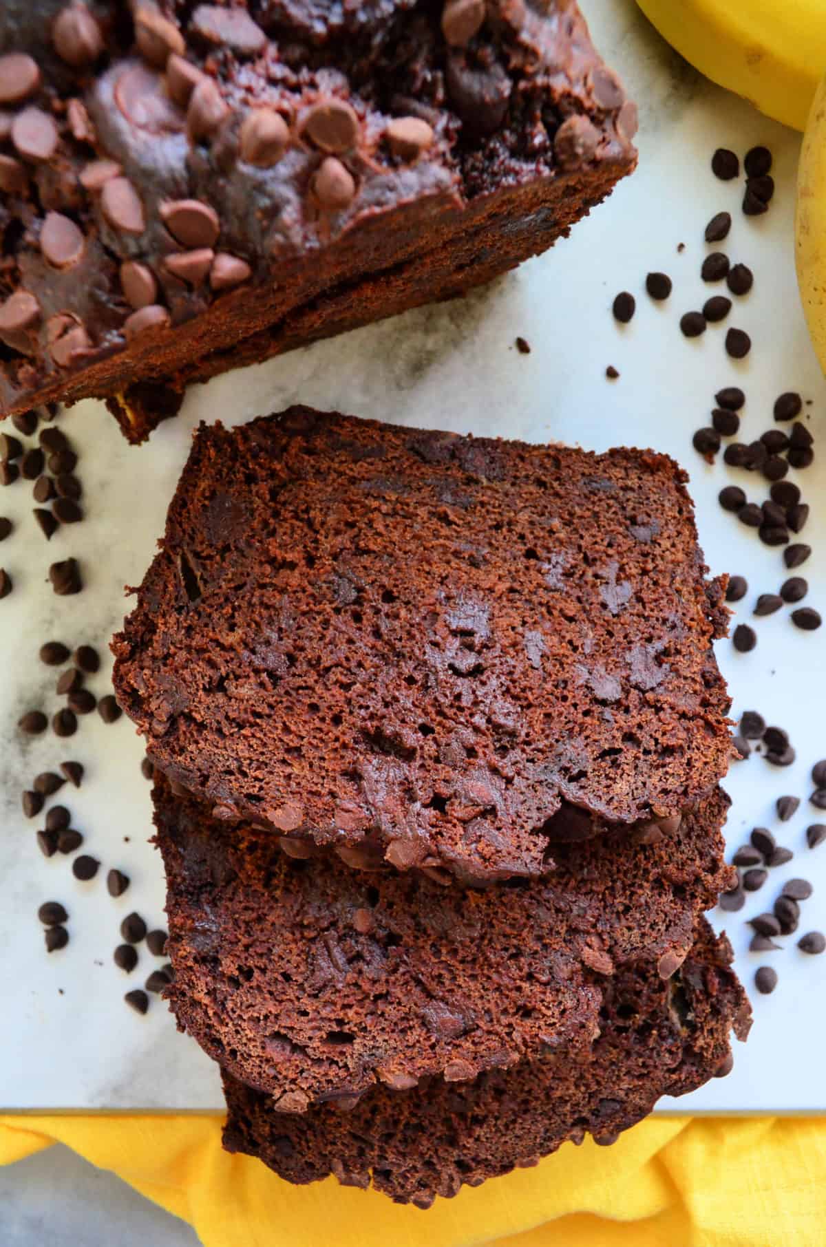 closeup top view of two slices of brown bread with chocolate chips in it and on counter below.