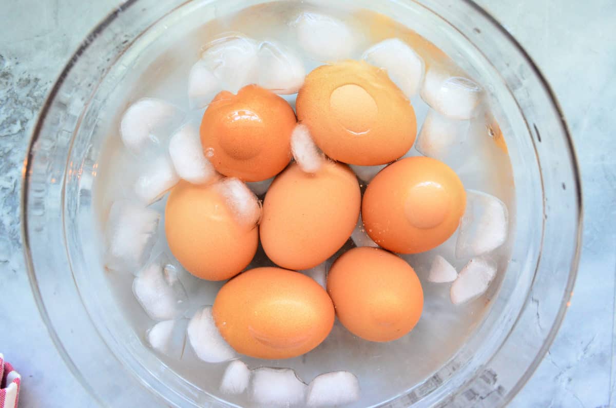 top view of glass bowl with 7 eggs and ice water.