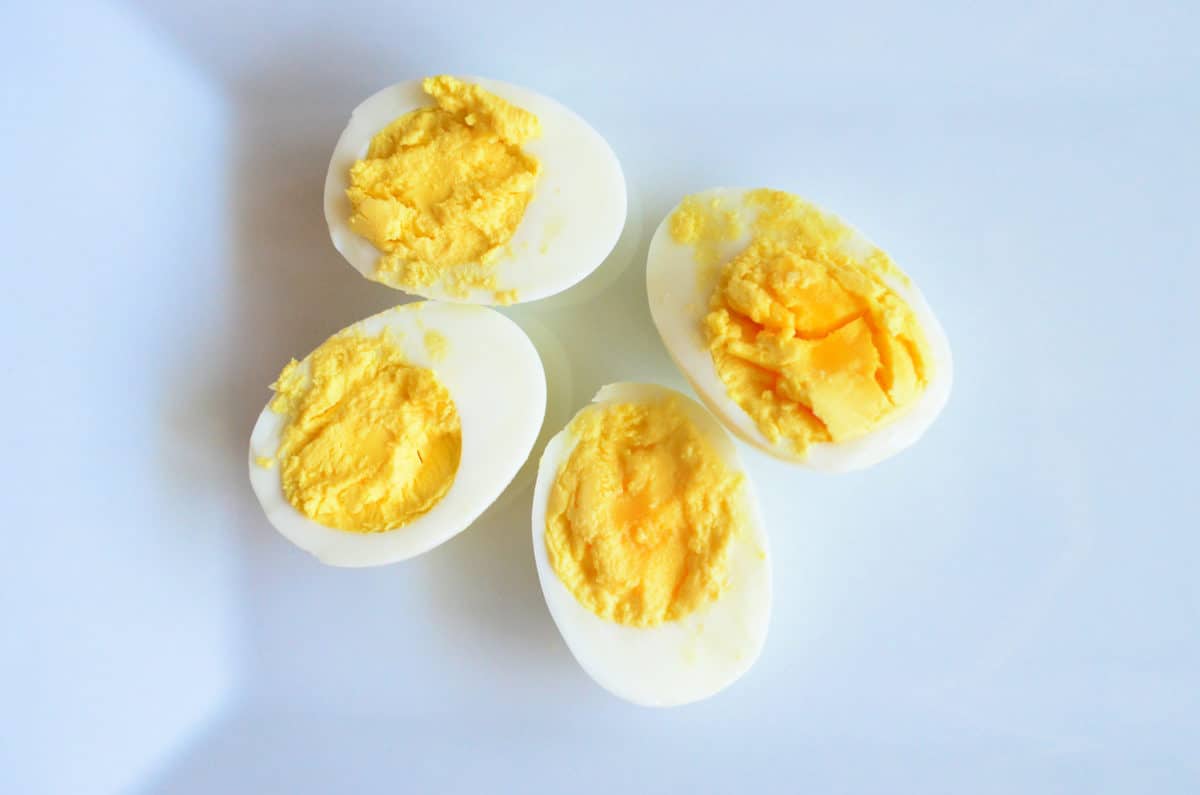 two halved hard boiled eggs resting whites down to expose cooked yoke center.