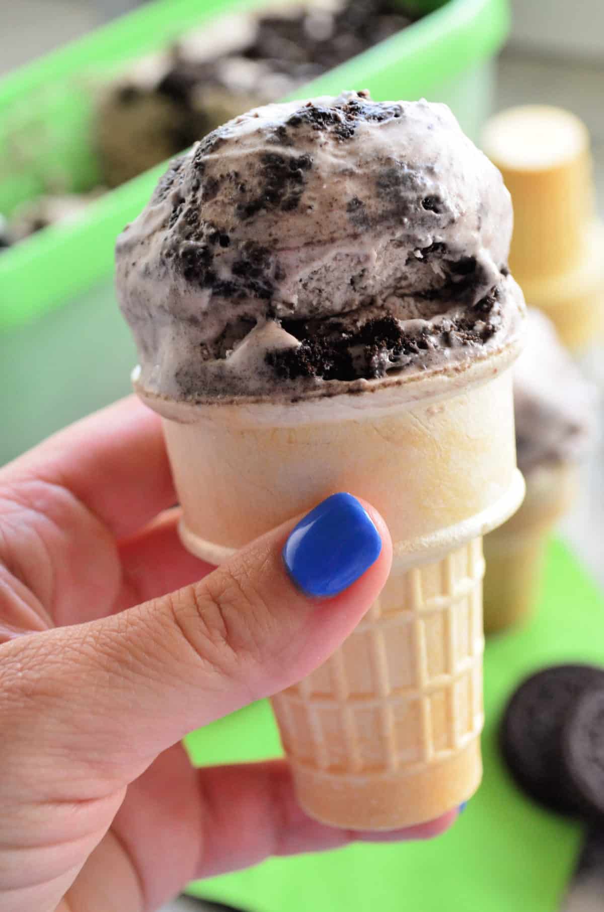 Close up of cone with one scoop of cookies and cream ice cream.