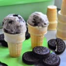 2 cones with one scoop each of cookies and cream ice cream on napkin next more cones.