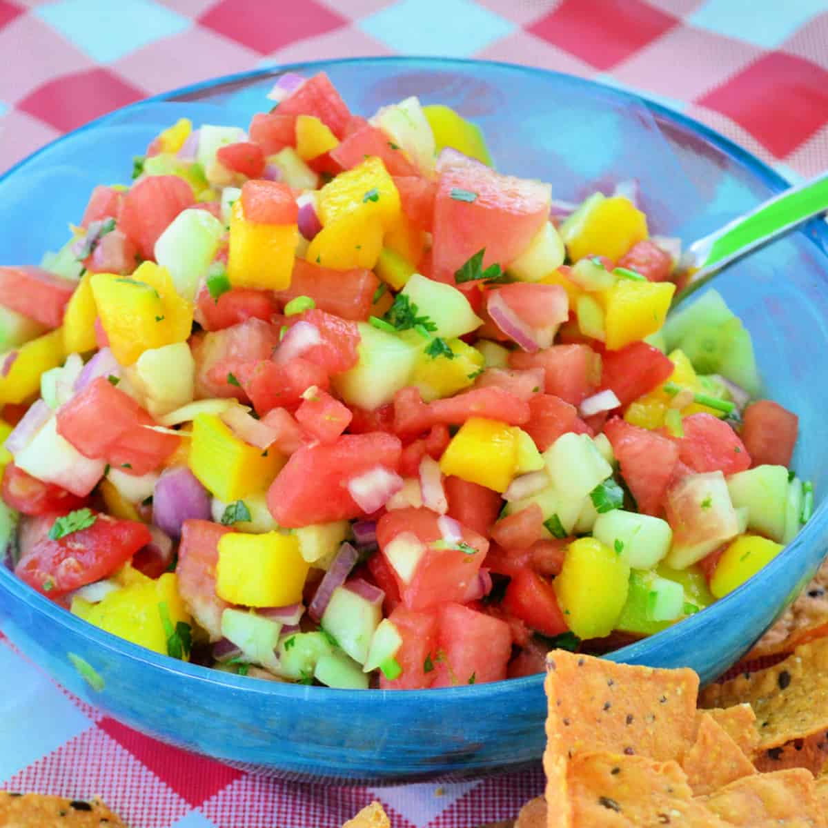 Blue bowl with watermelon salsa inside with a spoon.