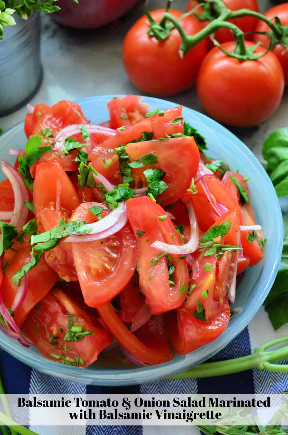 Tomatoes, red onion, basil, and dressing in bowl with whole tomatoes in background. title text.