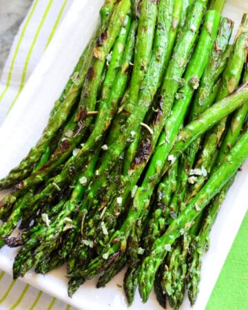 Top view of Grilled Italian Herb Asparagus on rectangle plate with pinterest title text.